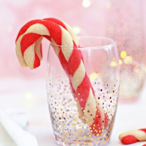 Candy Cane Cookies standing up in a clear glass with gold and silver dot accents.