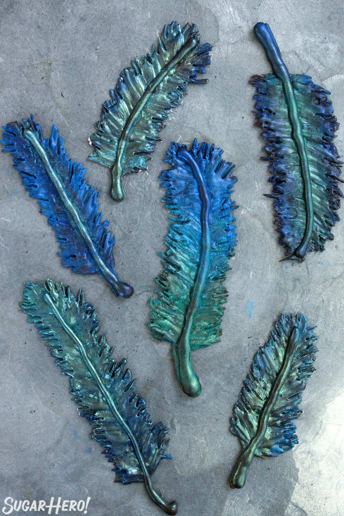 Chocolate feathers painted with blue and green luster dust on a silver platter.