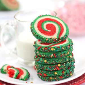 Stack of Christmas Pinwheel Cookies on a plate next to a glass of milk.