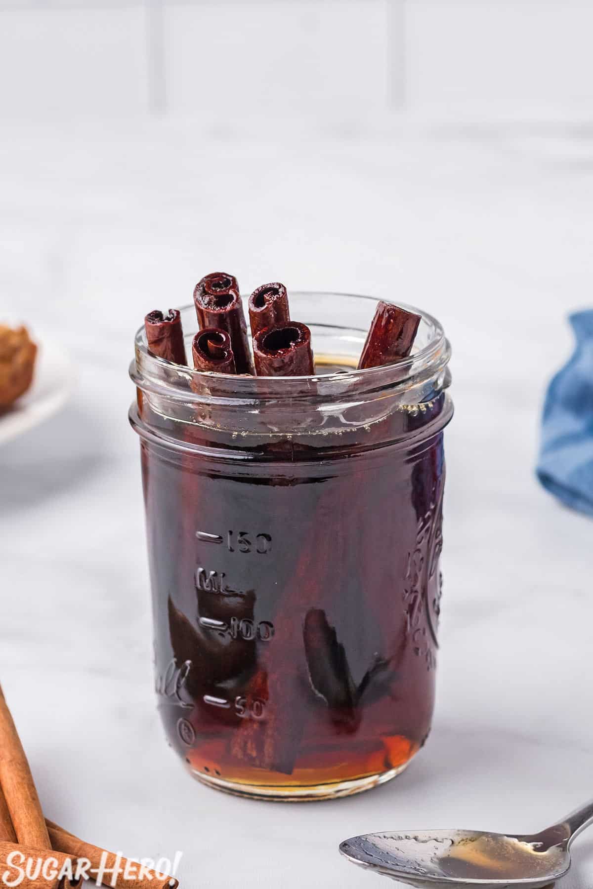 Jar full of Cinnamon Syrup, with cinnamon stick poking out of the top.