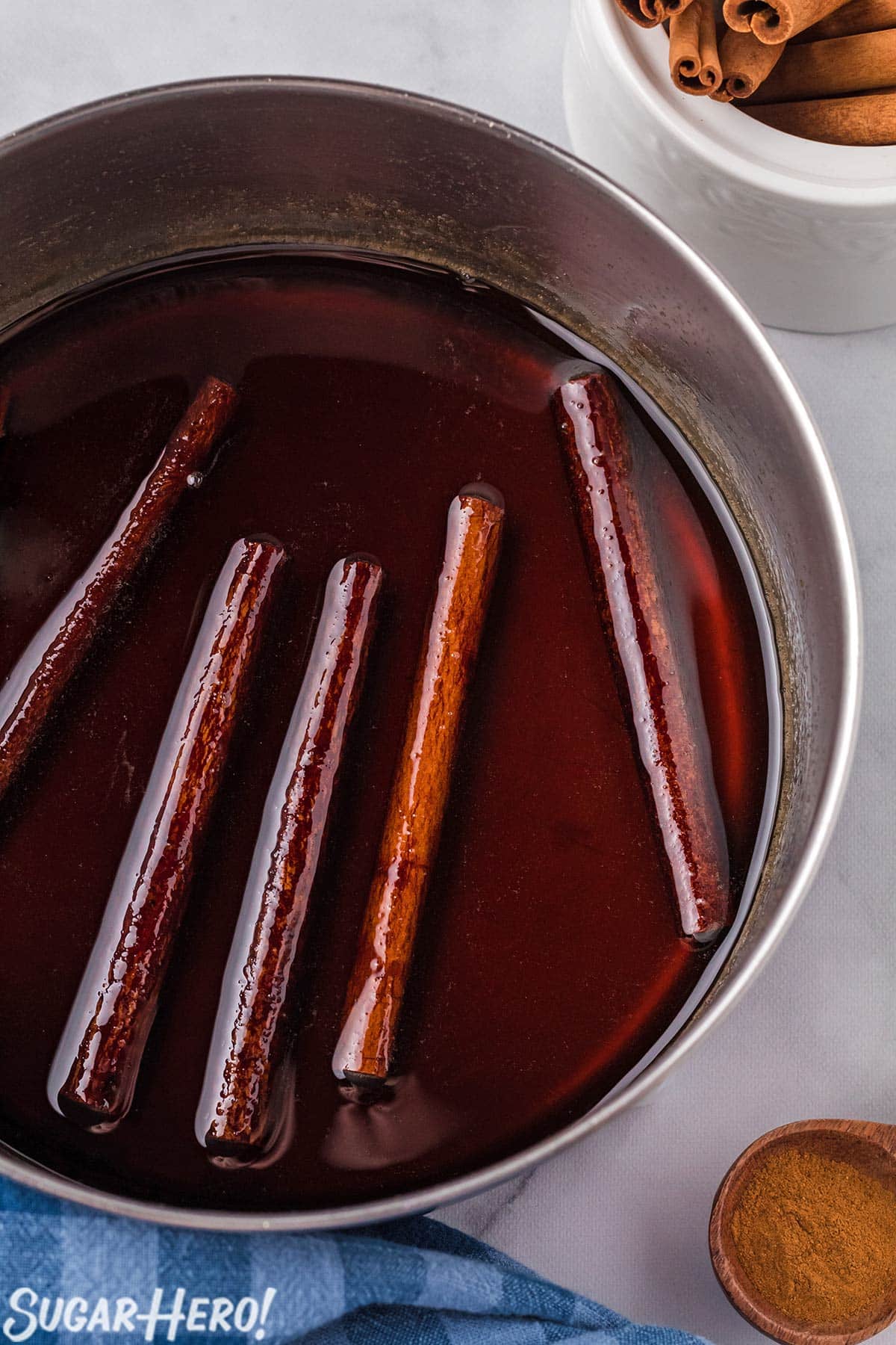 Close-up of saucepan full of Cinnamon Syrup with cinnamon sticks floating in it.