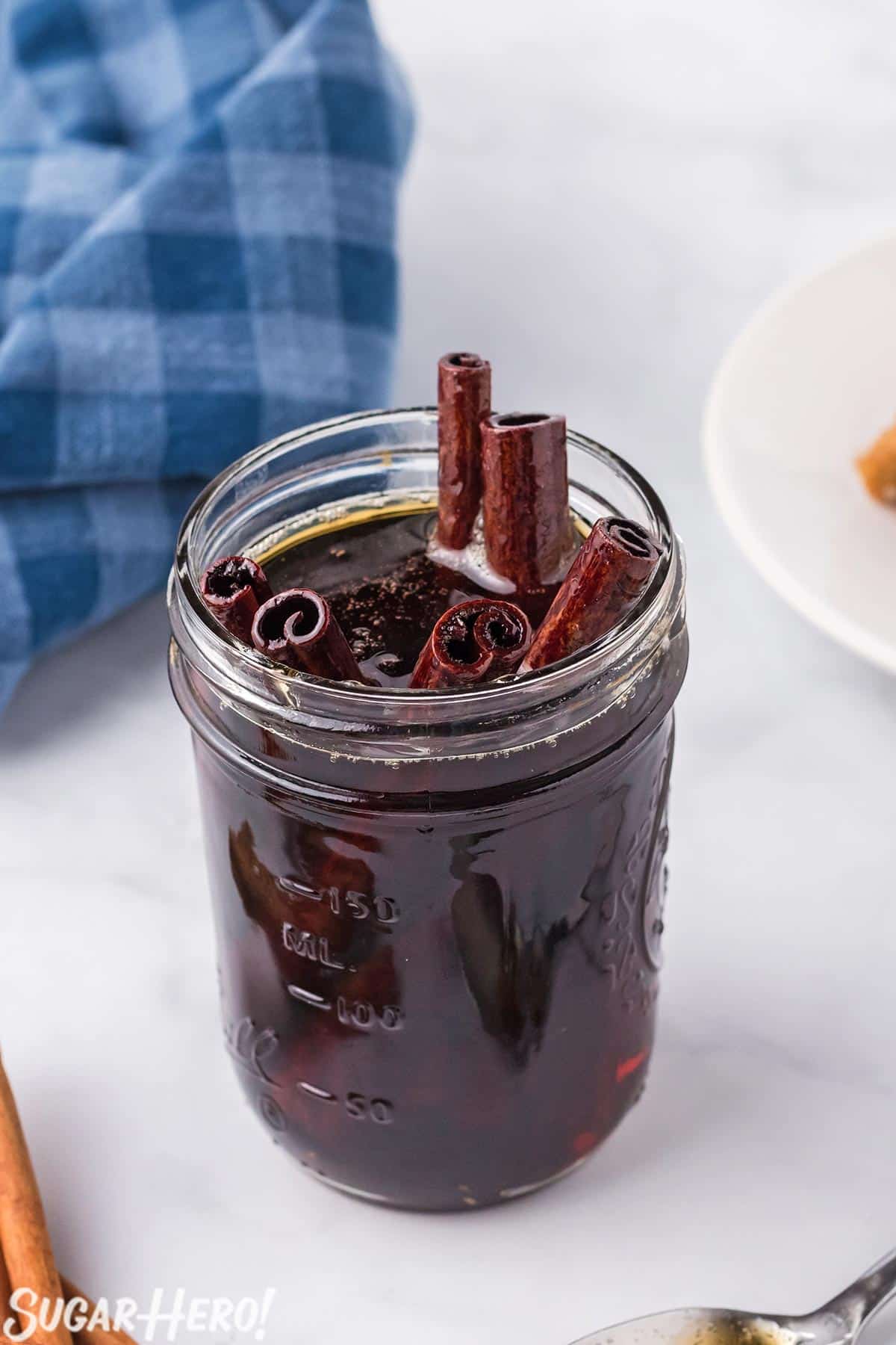 Jar full of Cinnamon Syrup, with cinnamon stick poking out of the top.