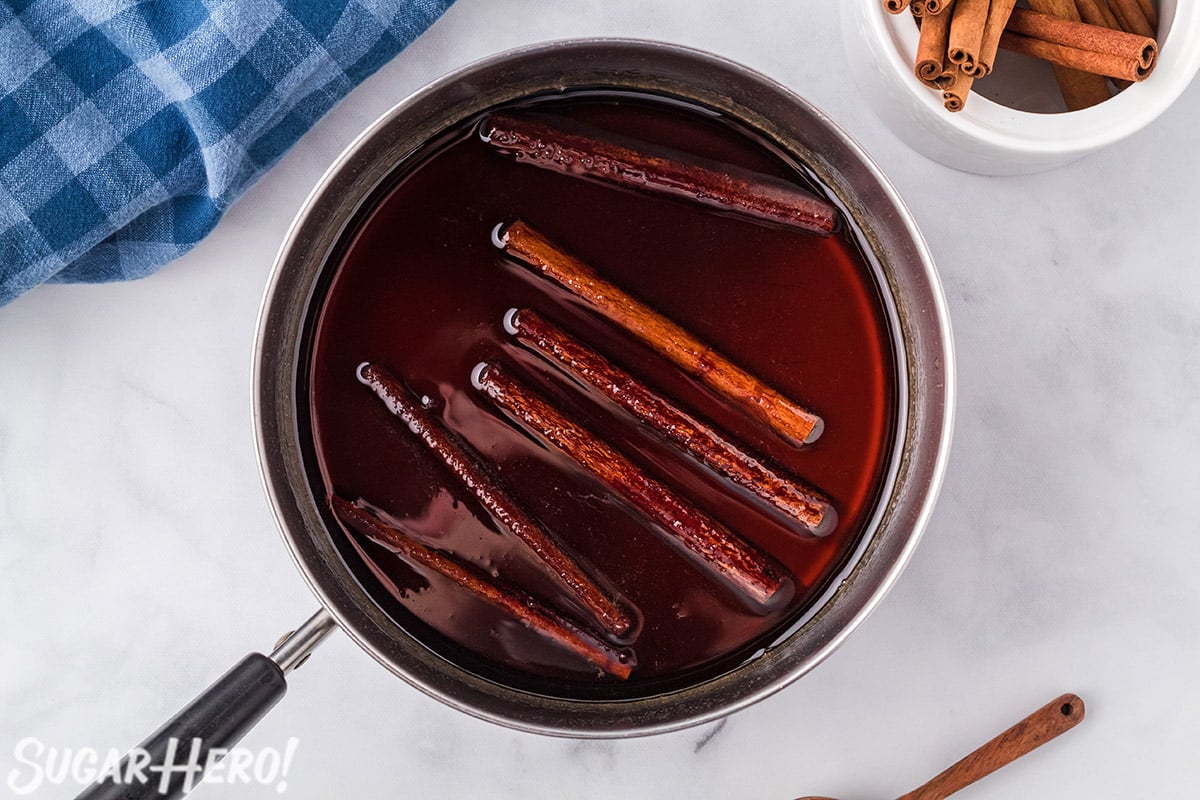 Overhead shot of saucepan full of Cinnamon Syrup with cinnamon sticks floating in it.