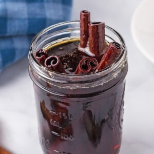 Jar full of Cinnamon Syrup, with cinnamon stick poking out of the top.
