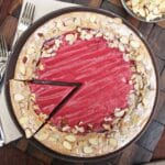 Cranberry Curd Almond Cake on a brown plate with a slice being removed.