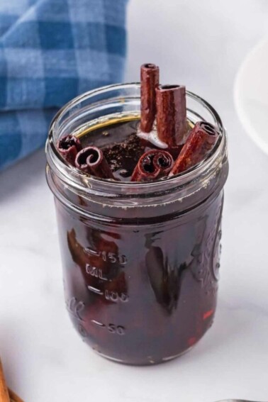 Jar full of Cinnamon Syrup, with cinnamon stick poking out of the top.