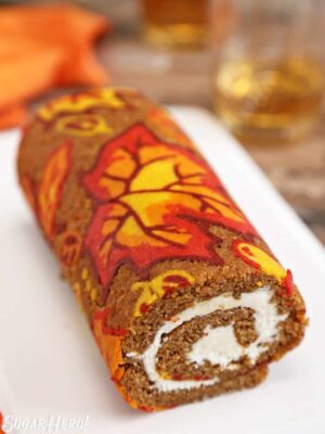 Patterned Pumpkin Roll on a white platter with an orange napkin in the background.