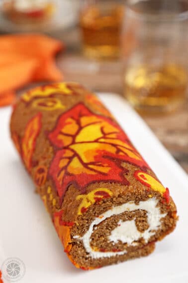 Patterned Pumpkin Roll on a white platter with an orange napkin in the background.