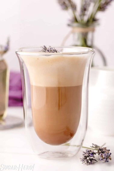 Lavender Latte in a clear glass jar with fresh lavender in the background.