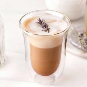 Lavender Latte in glass with sprig of fresh lavender on top.