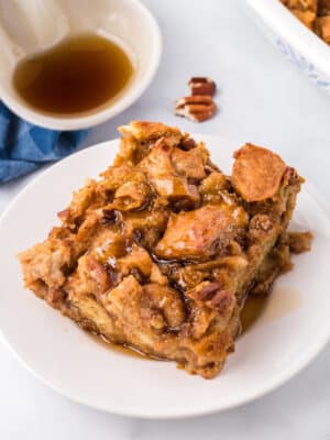 Slice of Pumpkin Bread Pudding on a white plate, drizzled with cinnamon syrup.