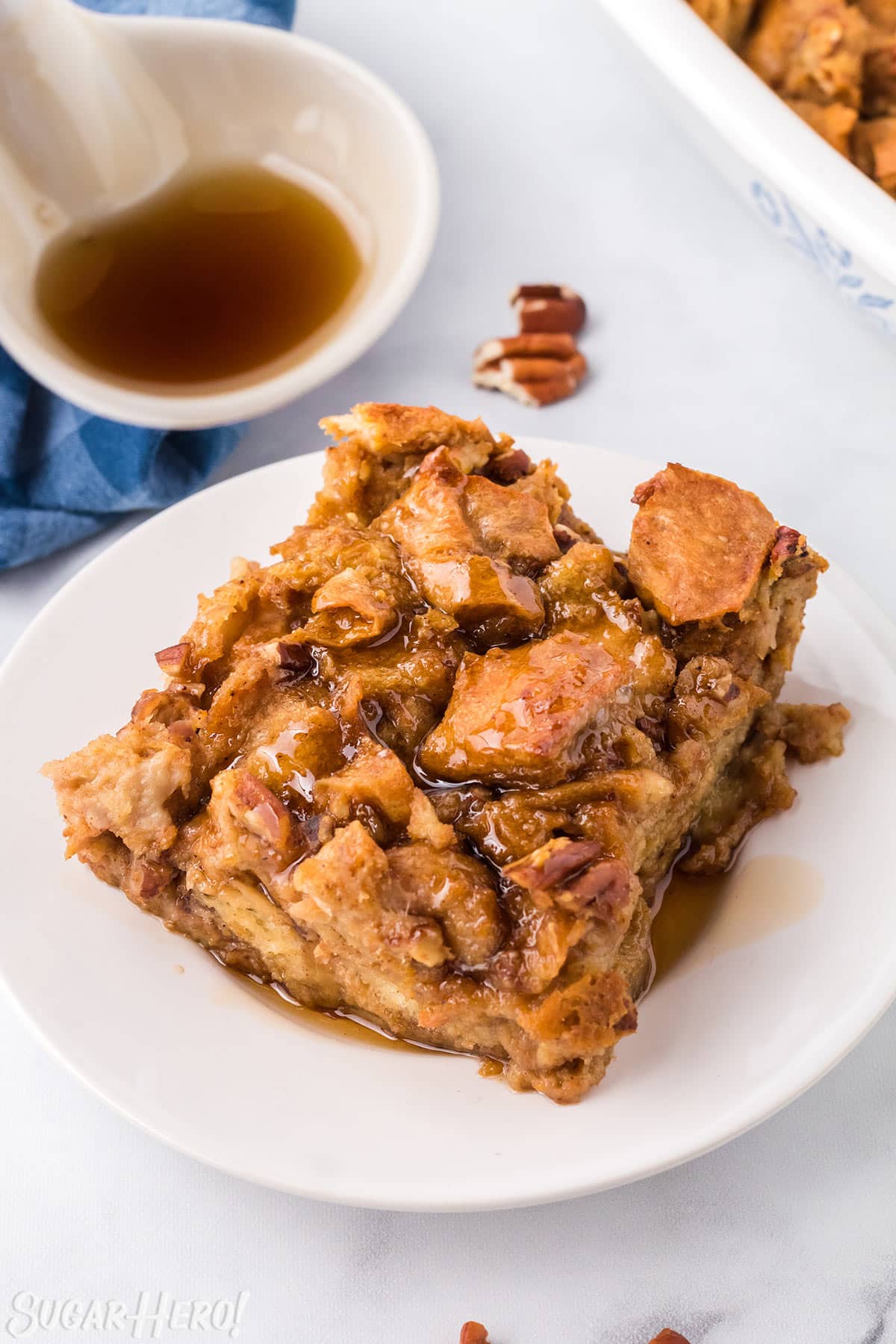 Slice of Pumpkin Bread Pudding on a white plate, drizzled with cinnamon syrup.