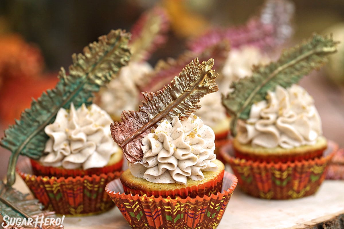 Three Spice Cupcakes on a wooden platter with fall-colored cupcake wrappers.
