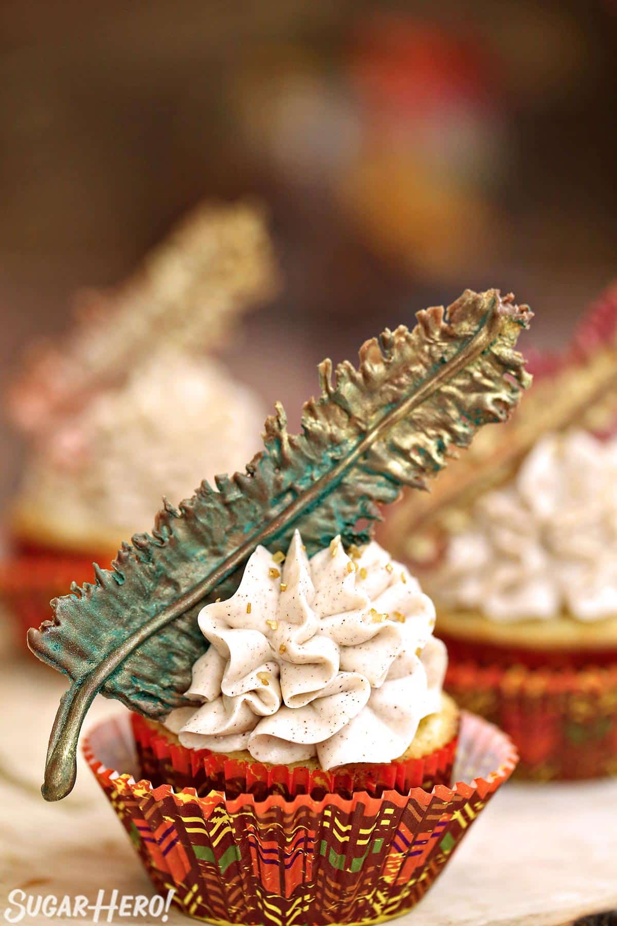 Spice cupcake on a wooden platter topped with cinnamon buttercream and a chocolate feather.