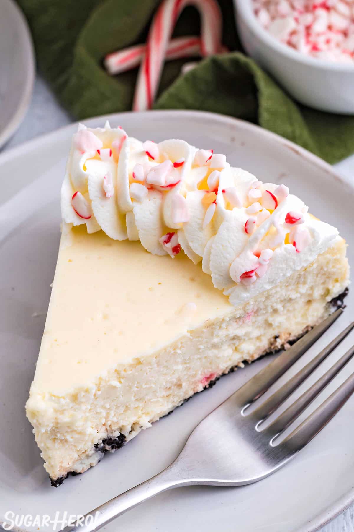 Candy Cane Cheesecake on a white plate with candy cane and a green napkin in the background.