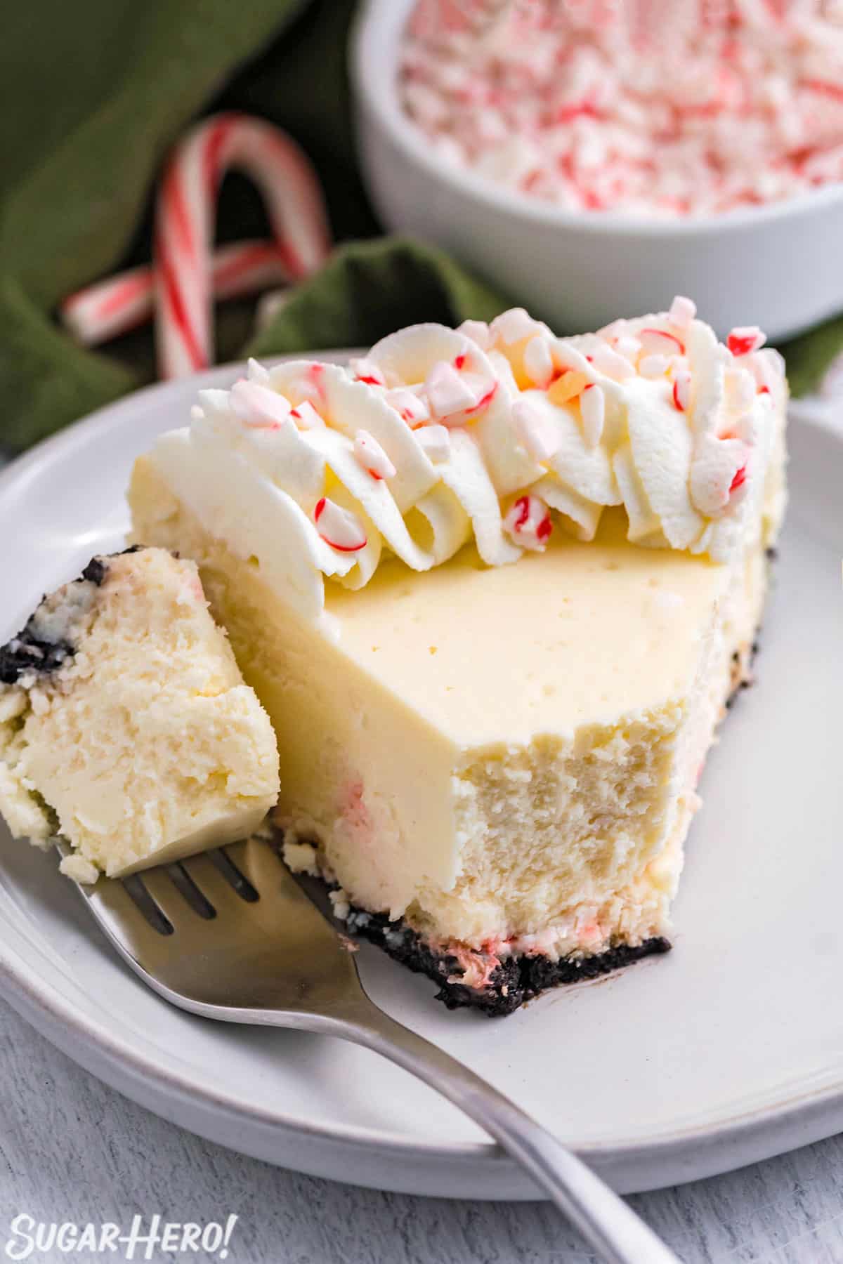 Slice of Candy Cane Cheesecake on a white plate, with a bite taken out of it.