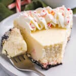 Candy Cane Cheesecake on a white plate with candy cane and a green napkin in the background.