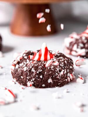 Close up of a Chocolate Peppermint Kiss Cookie with candy cane pieces being sprinkled on top.
