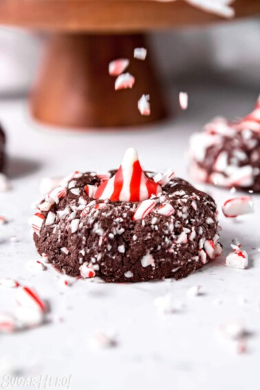 Close up of a Chocolate Peppermint Kiss Cookie with candy cane pieces being sprinkled on top.