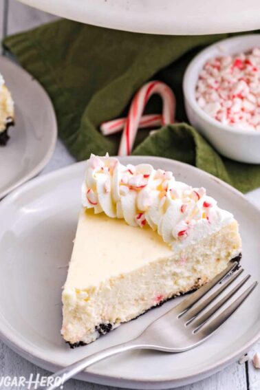 Candy Cane Cheesecake on a white plate with candy cane and a green napkin in the background.