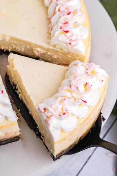 Cake server removing a slice of Candy Cane Cheesecake from a serving platter.