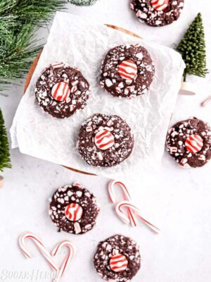 Top view of an assortment of Chocolate Peppermint Kiss Cookies next to evergreen trees and candy canes.