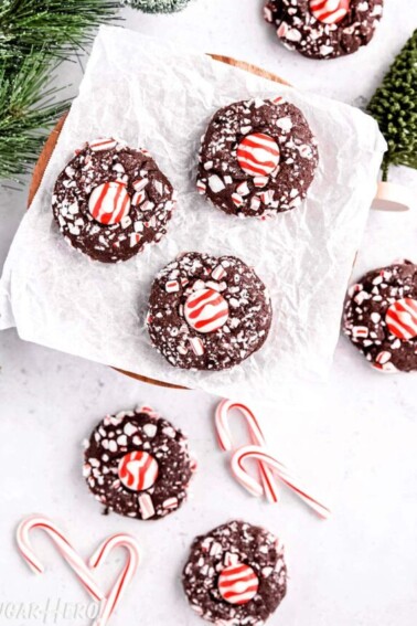 Top view of an assortment of Chocolate Peppermint Kiss Cookies next to evergreen trees and candy canes.