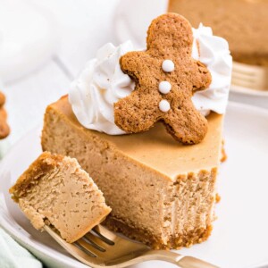 Slice of Gingerbread Cheesecake on a white plate with a bite removed on a fork.
