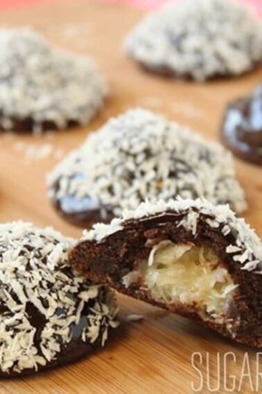 Mounds Cookies on a wooden surface with one cookie cut open to show filling.