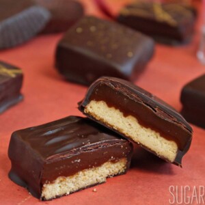 Caramel shortbread squares cut open on an orange surface.