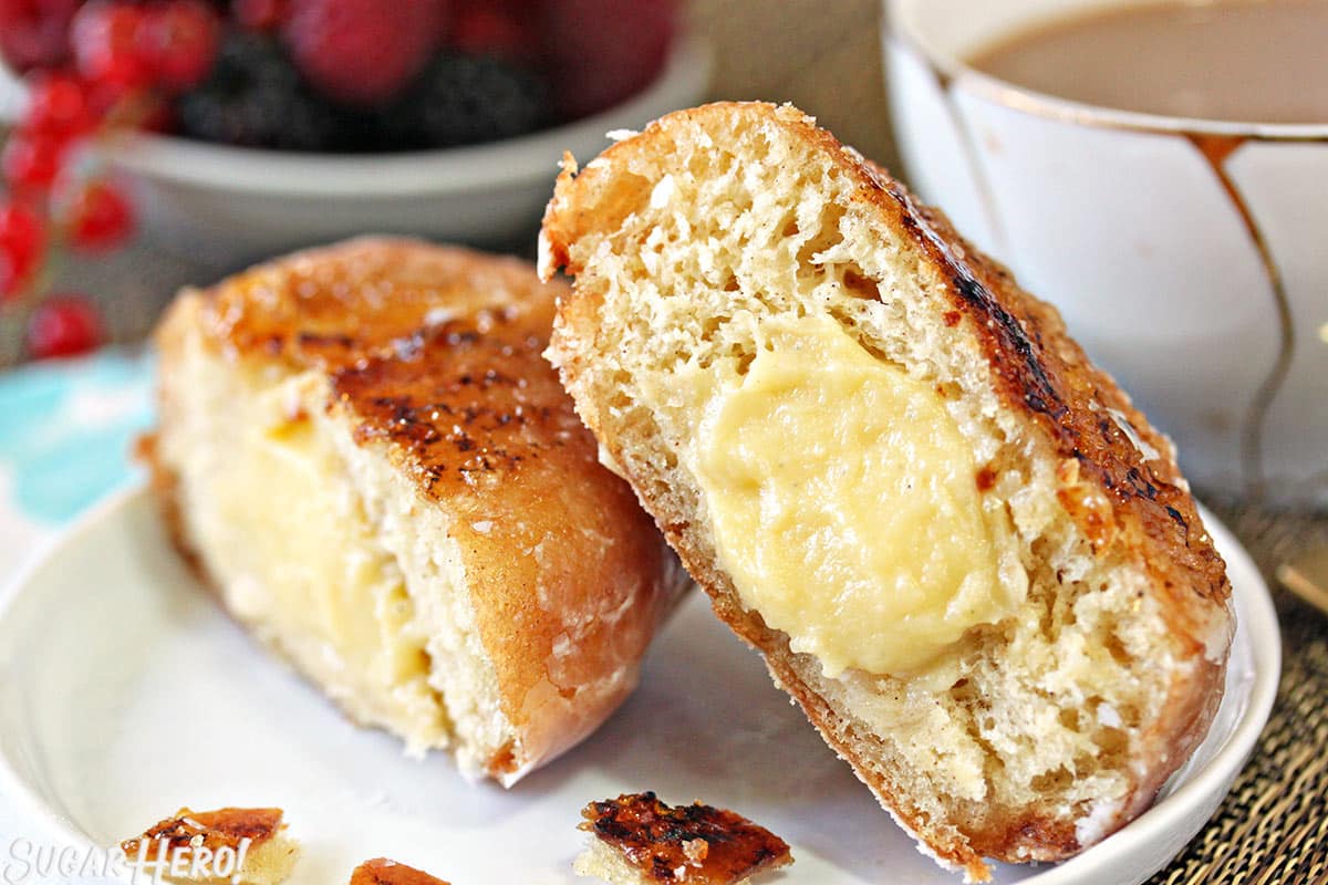 A Crème Brûlée Donut cut in half to show the vanilla pastry cream filling in the center.