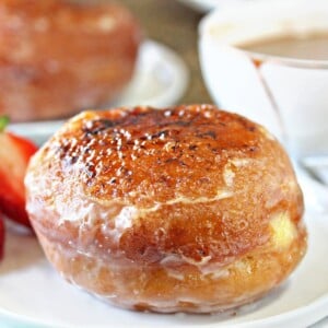 Close-up of a Crème Brûlée Donut on a white plate with more donuts in the background.