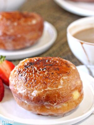 Crème Brûlée Donuts on white plates among cups of tea and fresh berries.