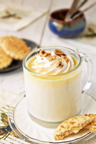 Mug of Hazelnut White Hot Chocolate with cookies in the background.