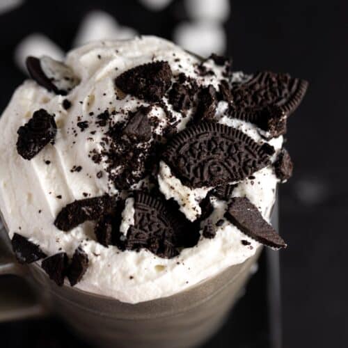 Top view of a cup of Oreo Hot Chocolate with lots of whipped cream and crushed Oreos.