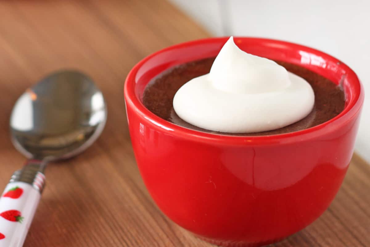 Salted Caramel Chocolate Mousse in a red bowl with a dollop of whipped cream.