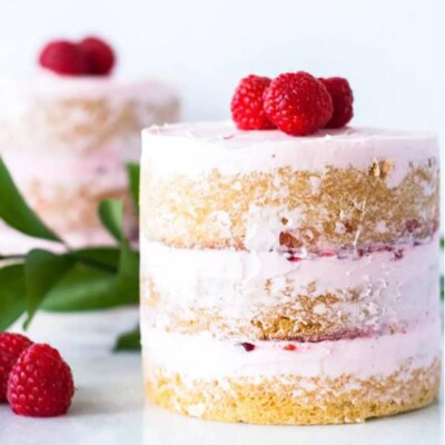 Close up of a Raspberry Vanilla Mini Cake next to ruscus and raspberries.