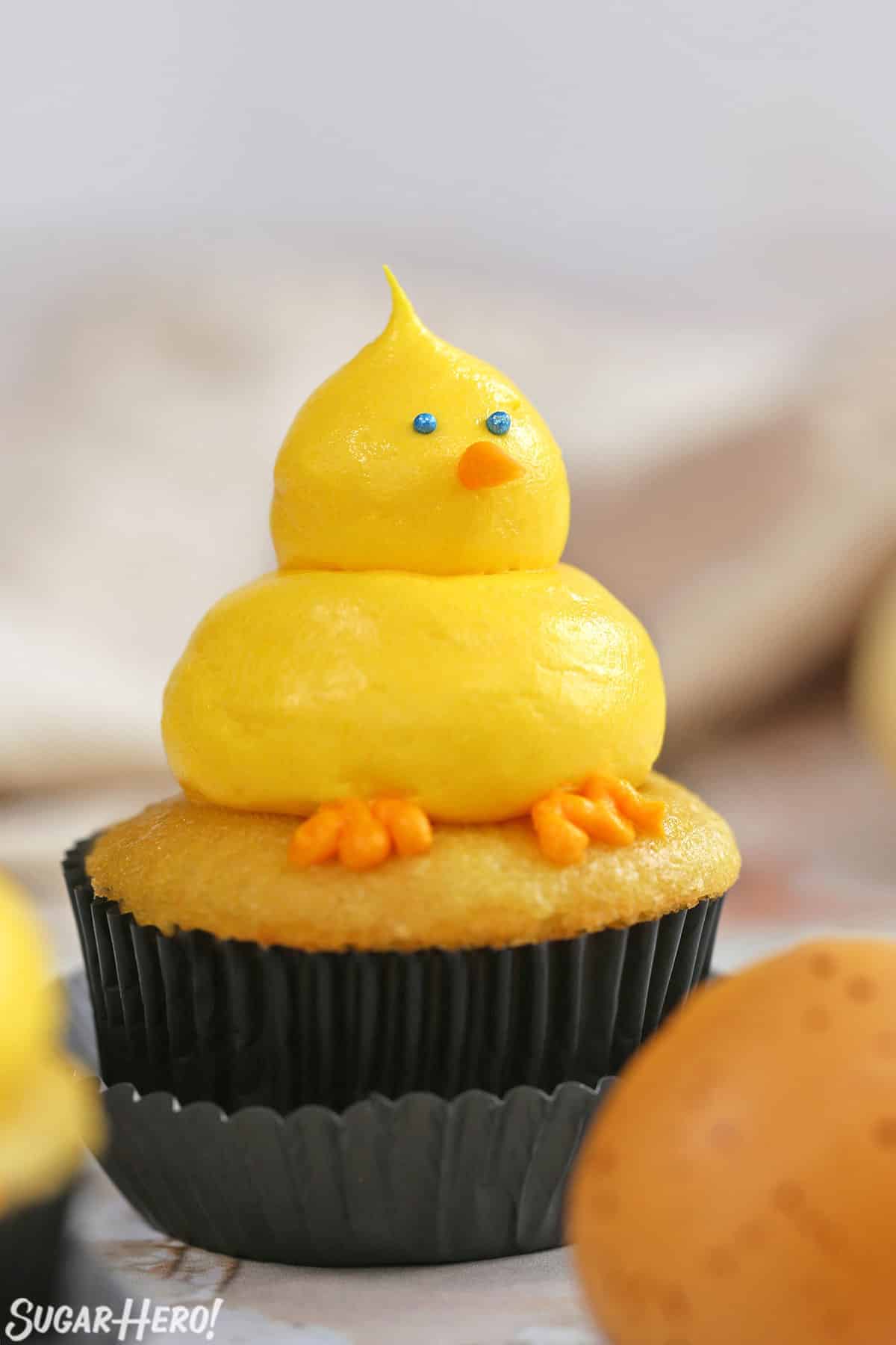 Side view close up of a Baby Chick Cupcake with a brown egg in the foreground.