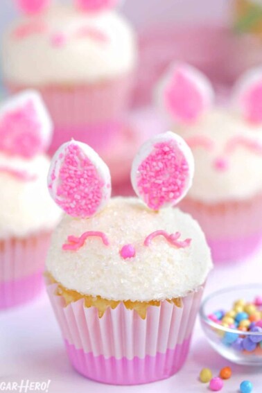 4 Easter Bunny Cupcakes next to a small bowl of sprinkles.