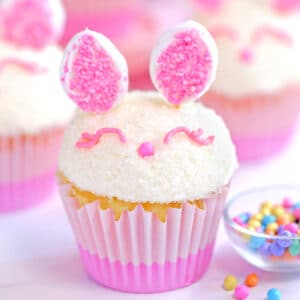 Close up of an Easter Bunny Cupcake next to sprinkles.