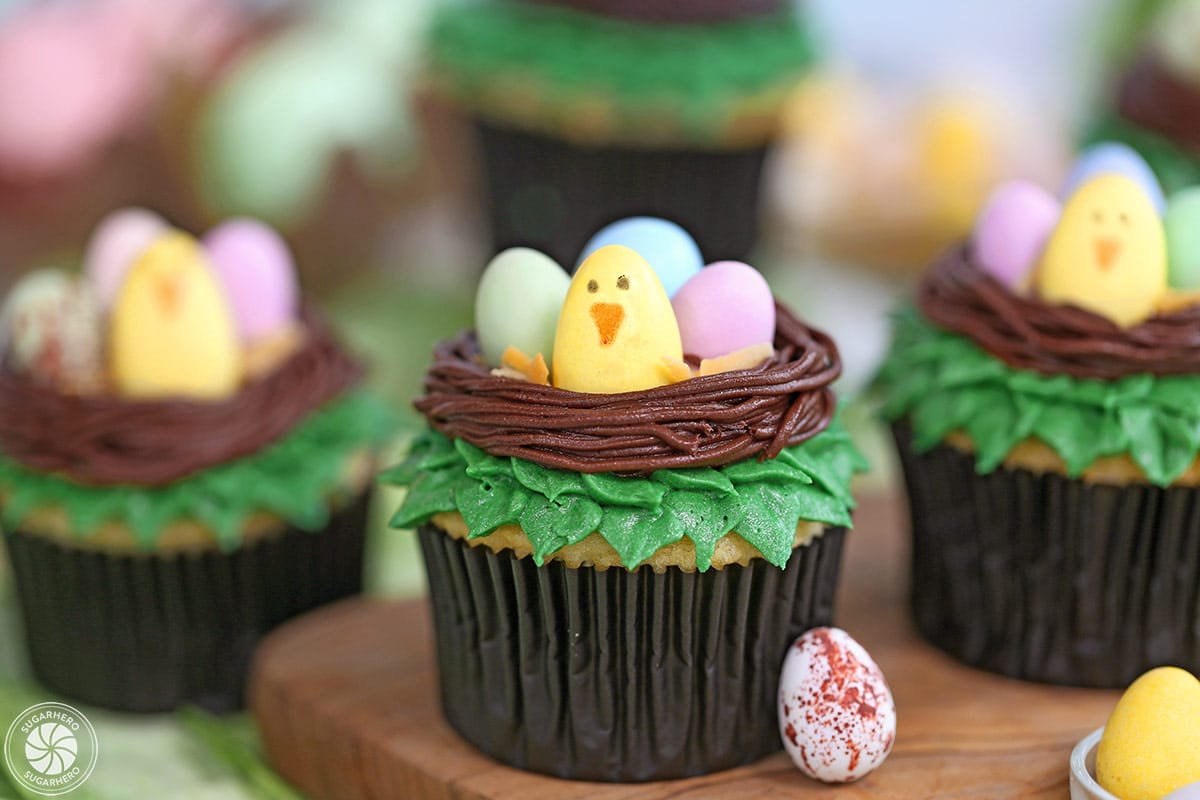 Easter Bird's Nest Cupcakes on a wooden surface with candy eggs around the base.