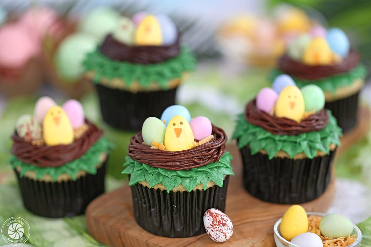 Five Easter Bird's Nest Cupcakes with leaves and candy eggs scattered around.