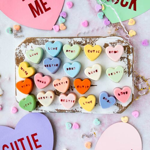 Top view of Heart Shaped Cake Bites on a rectangular serving platter next to conversation hearts.
