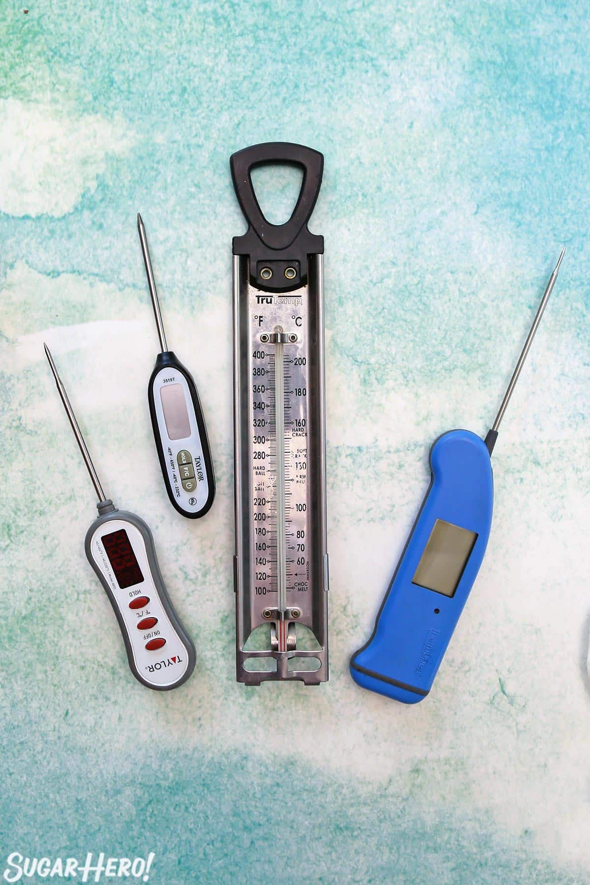 Overhead shot of four thermometers on a blue-green background.