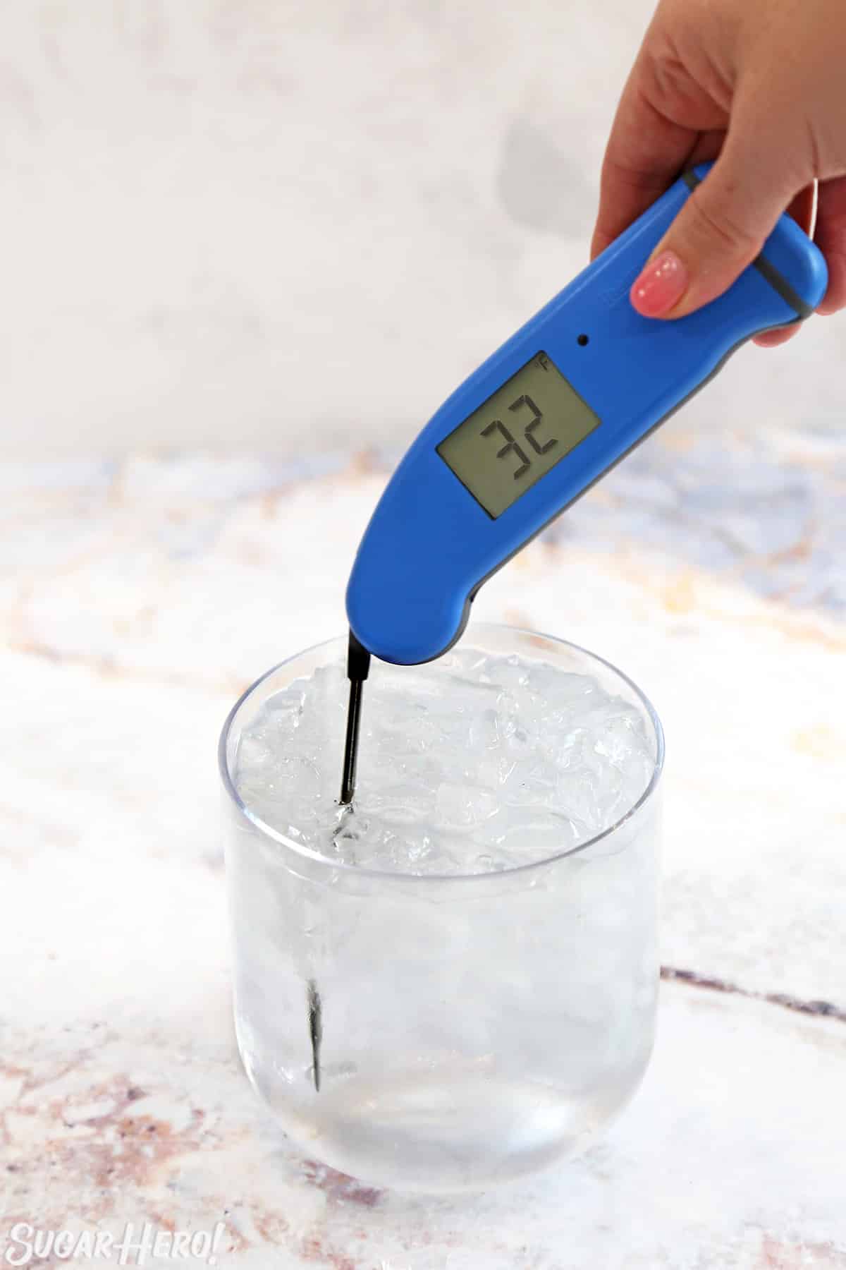 Placing a thermometer in a cup of ice water to test its accuracy.