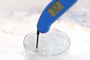Photo of placing a thermometer in a glass of ice water, with text overlay for Pinterest.