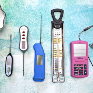 Five different candy thermometers arrayed on a green-blue background.