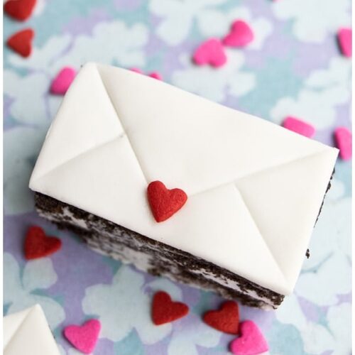 Top view of a Love Letter Mini Cake on a multi-colored background sprinkled with hearts.