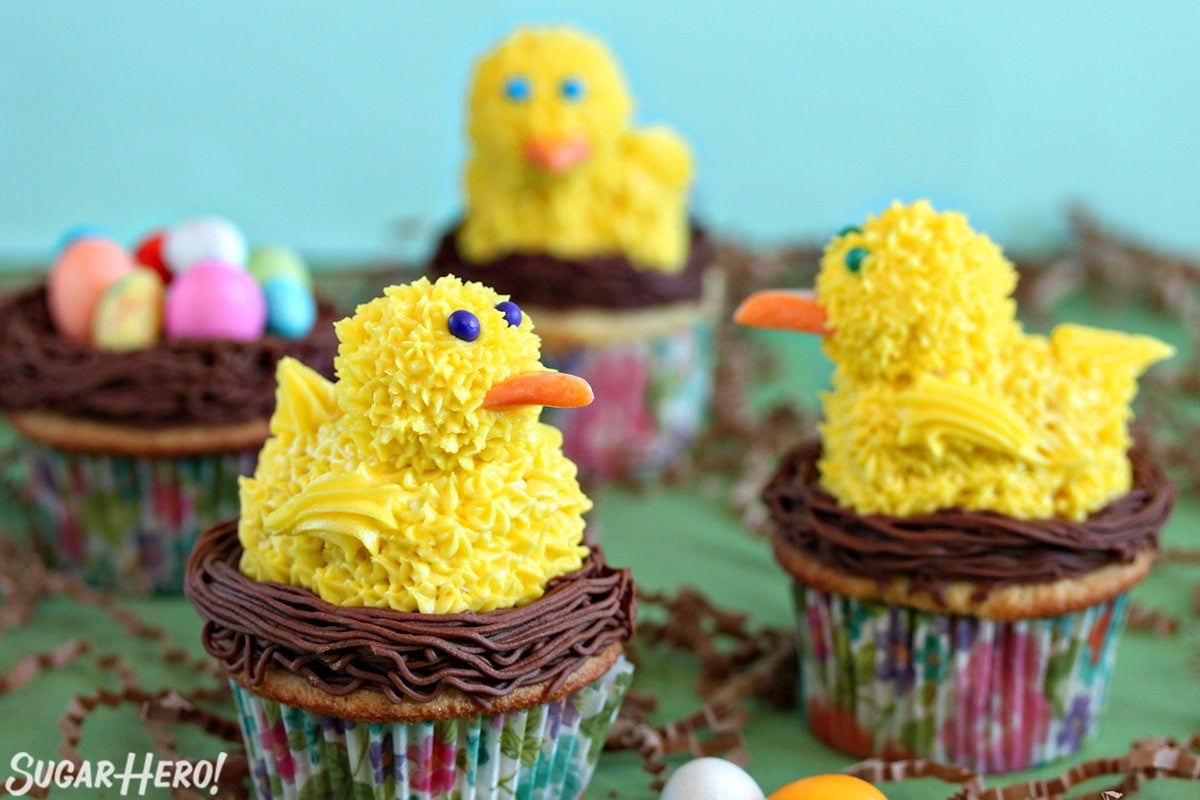 3 Spring Chick Cupcakes on a green surface.