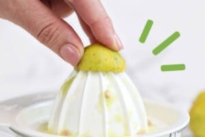 Photo of juicing a key lime on a white countertop juicer, with text overlay for Pinterest.